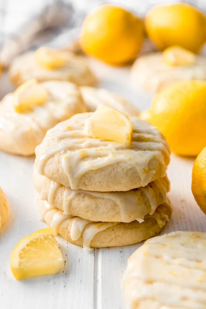 a stack of glazed lemon cookies with wedges of lemon next to them