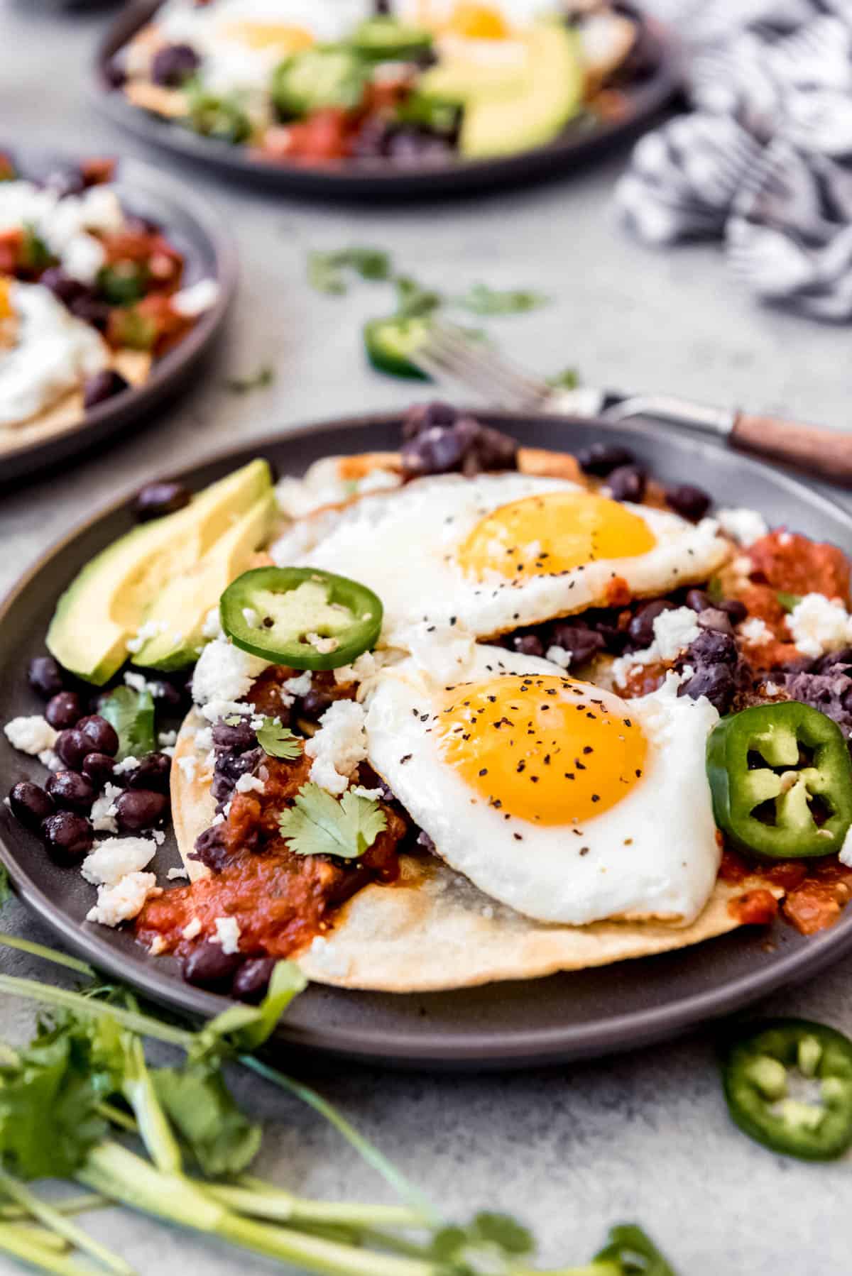 two huevos rancheros on a plate topped with jalapenos and cheese