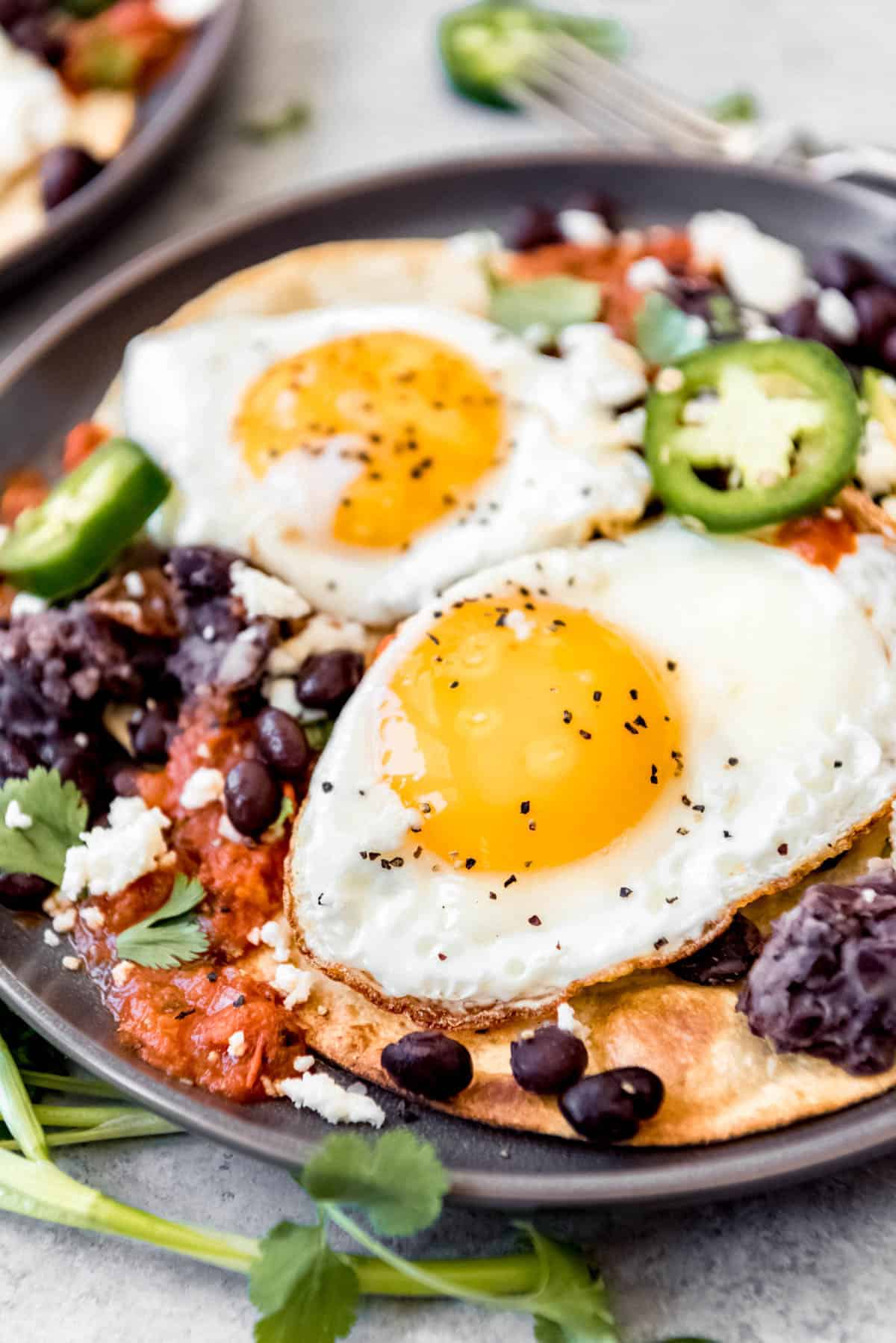 two fried eggs, on top of a bed of beans and ranchero sauce, atop of crispy tortillas