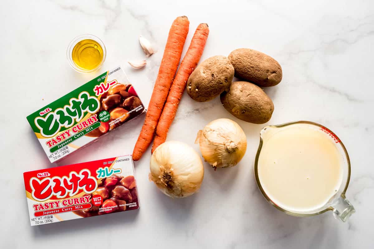 Ingredients used to create Japanese curry sauce, including curry mix, onions, potatoes, carrots, garlic, oil and chicken broth. 