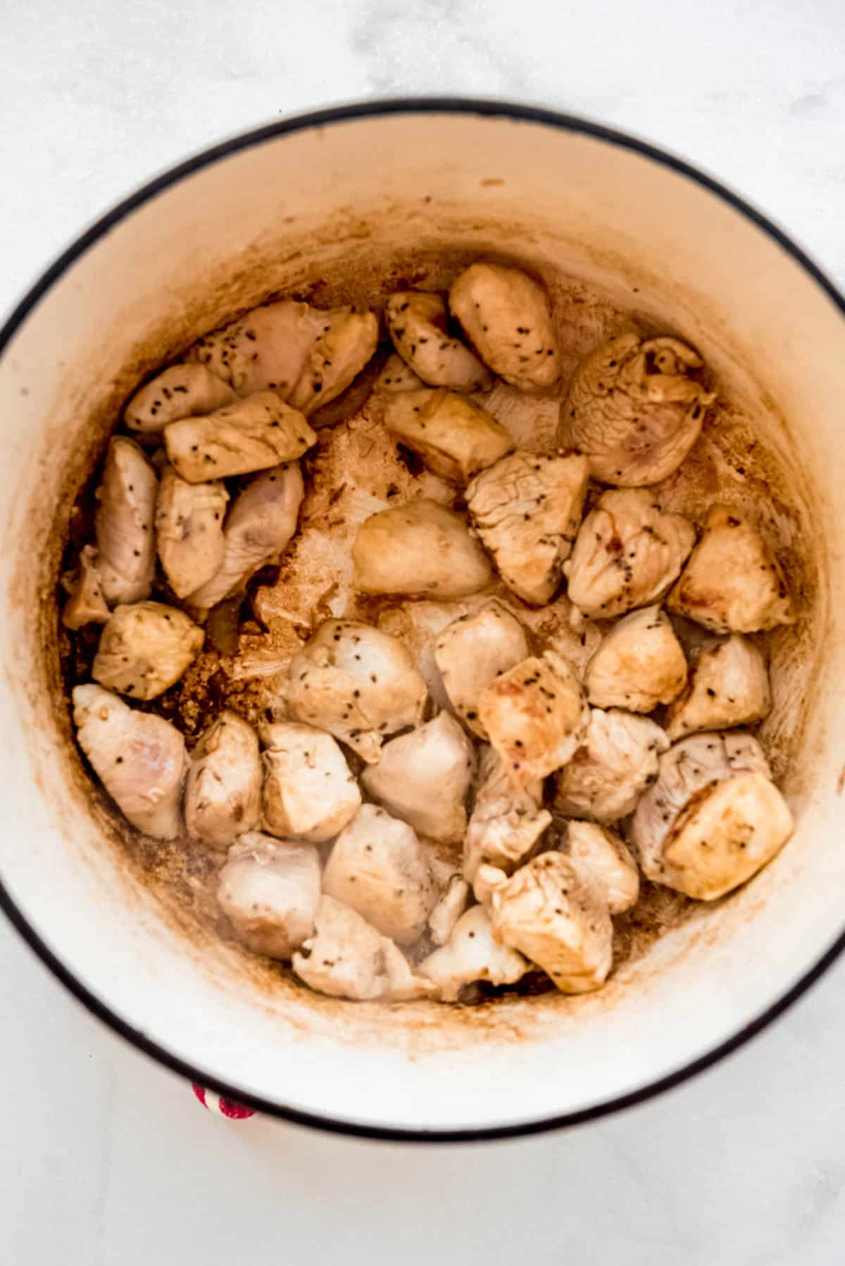 Browned chicken is resting in a dutch oven after being cooked. 