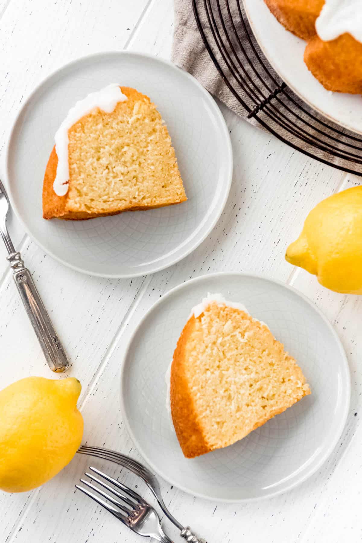 Two slices of iced lemon bundt cake, on serving plates. 