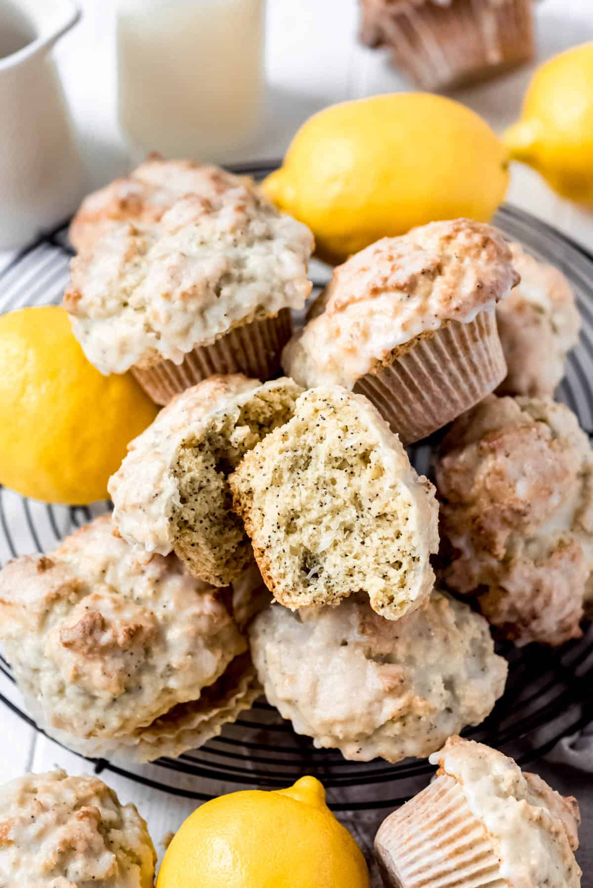 a lemon poppy seed muffin split open on top of a pile of more muffins and lemons