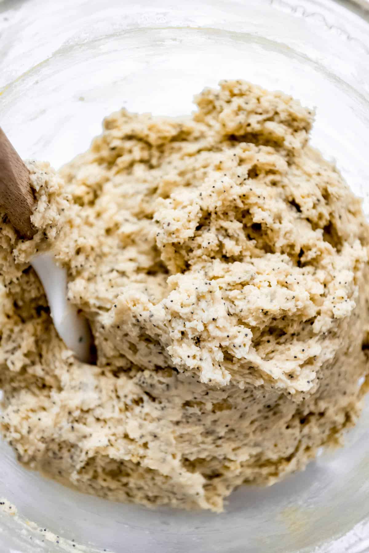 Lemon poppy seed muffin batter is blended with a wooden spatual. 