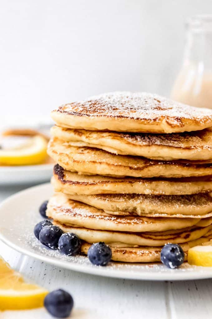 a stack of fluffy pancakes with lemon slices and blueberries on the side