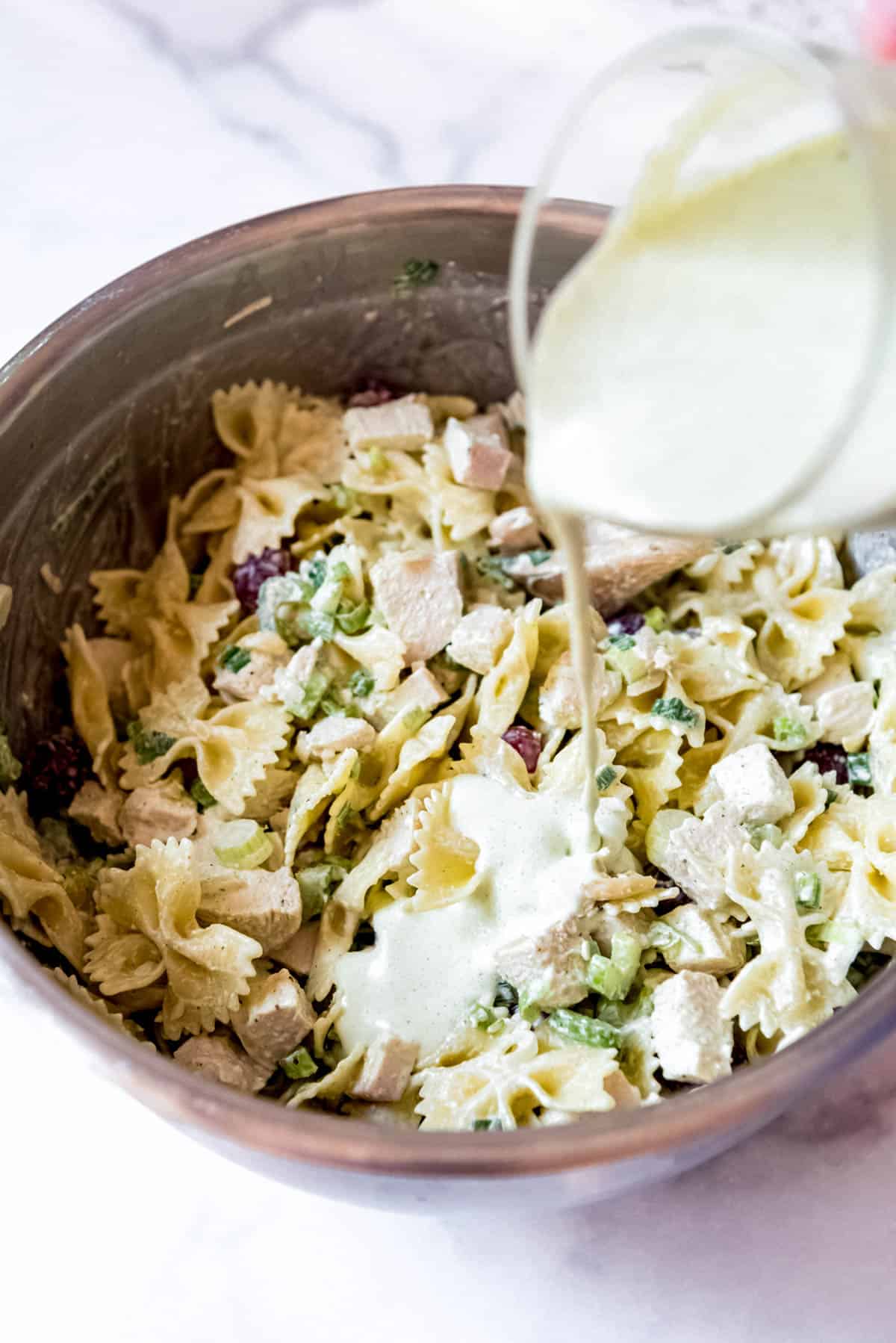 Adding dressing to a pasta salad.