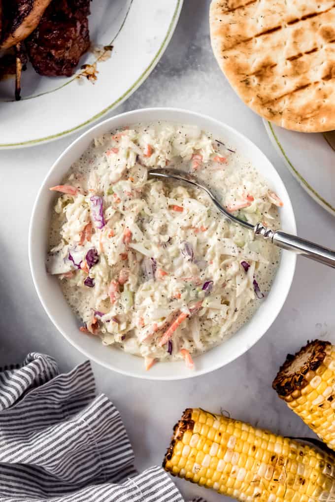 a bowl of homemade coleslaw next to corn on the cob