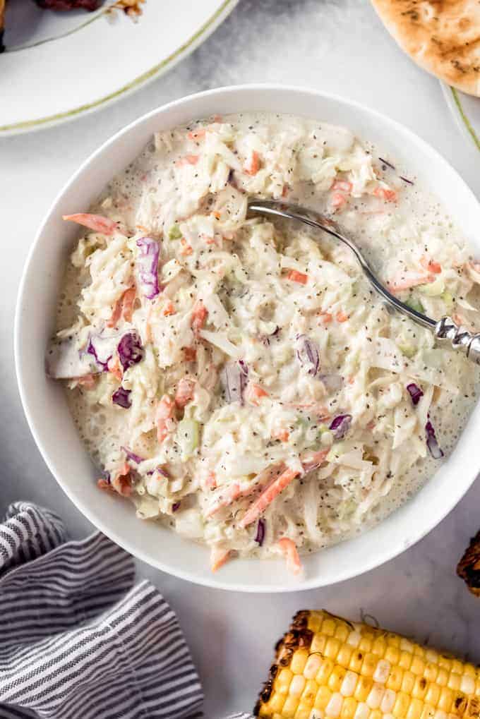 a bowl of creamy homemade coleslaw with a spoon in it for serving