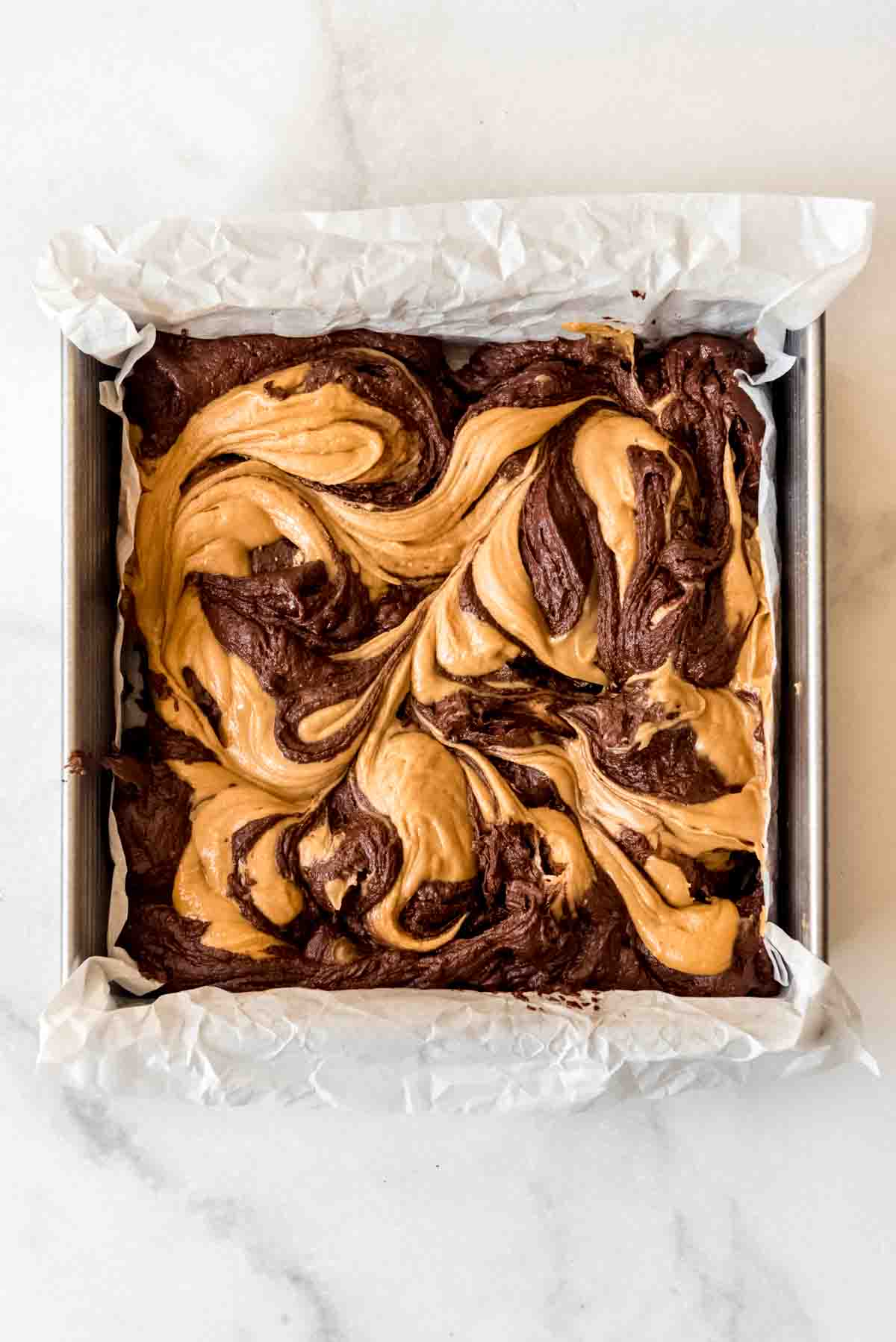 Swirled peanut butter brownies batter in a square pan.