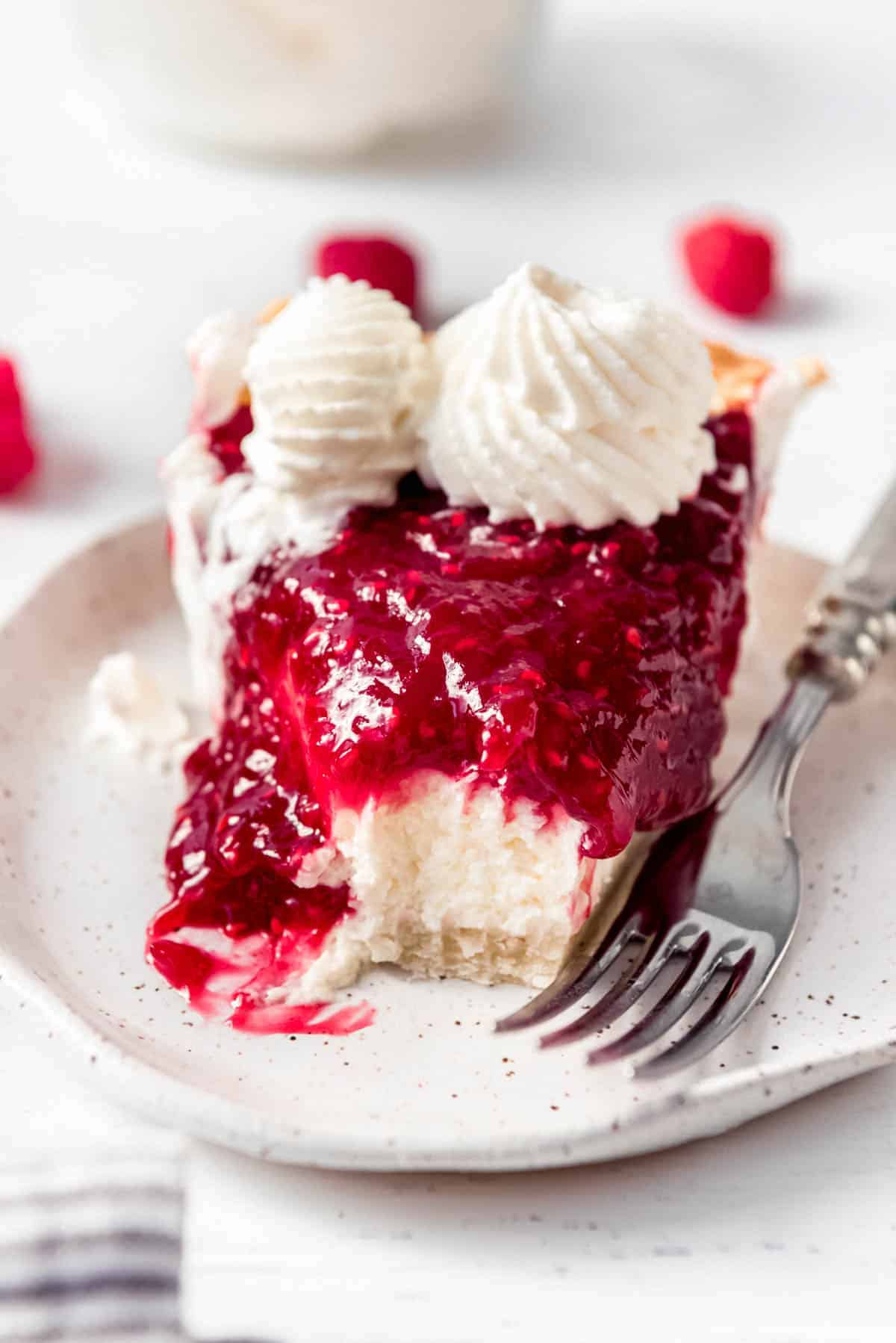 a slice of raspberry cream pie on a plate with a fork next to it