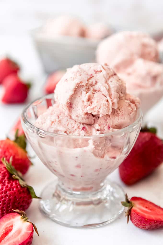 a small dish of strawberry ice cream surrounded by fresh strawberries