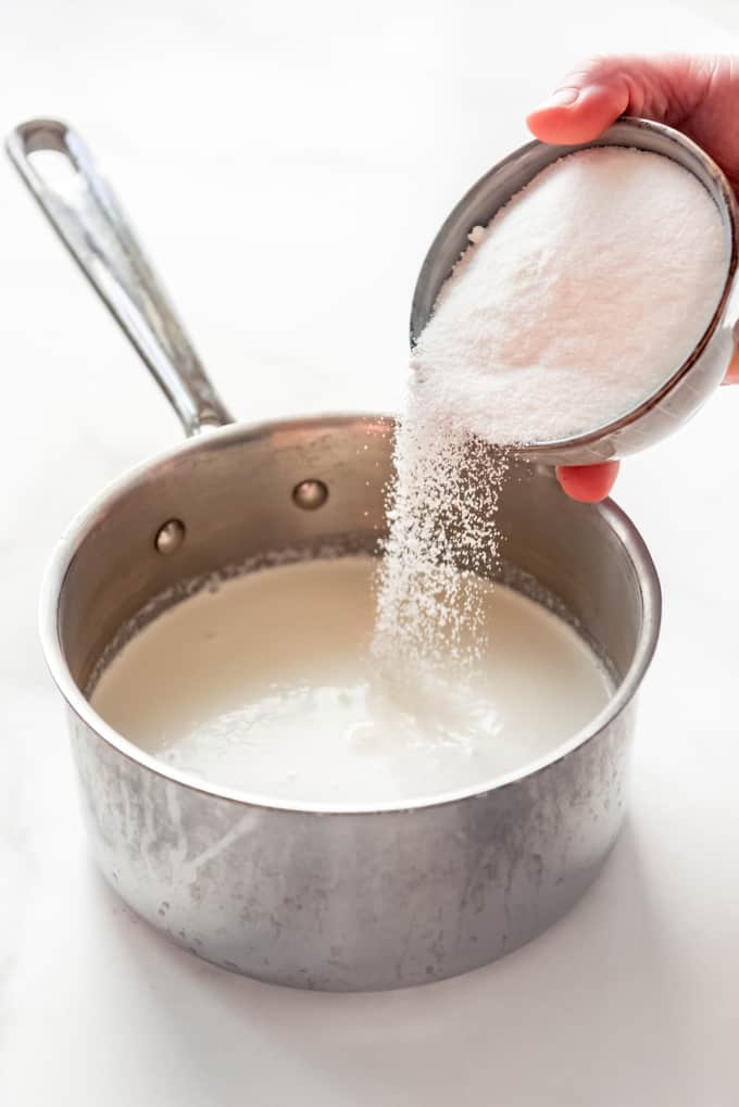 sugar being added to milk and cream in a saucepan
