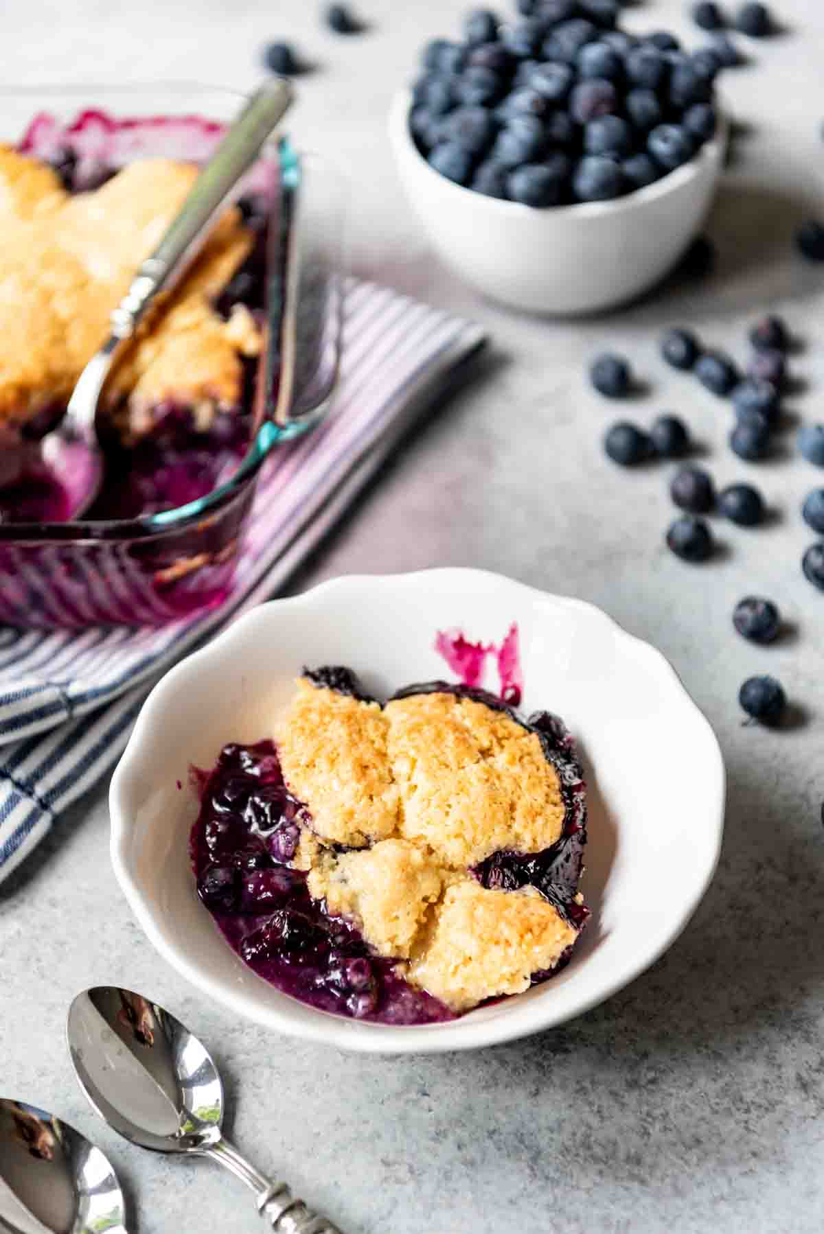 A serving of homemade blueberry cobbler is placed in a white bowl. 