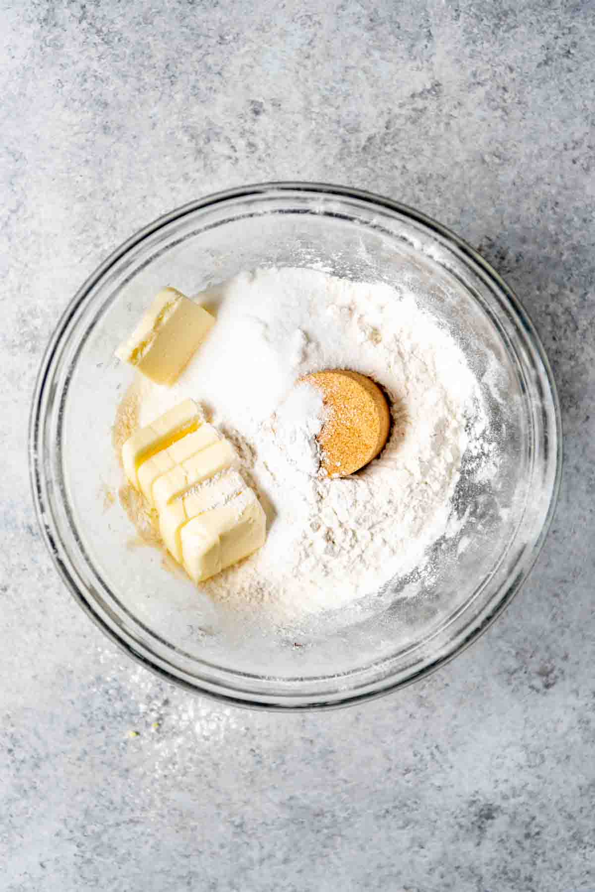 Chunks of butter are resting in a bowl with other ingredients to make a blueberry cobbler. 