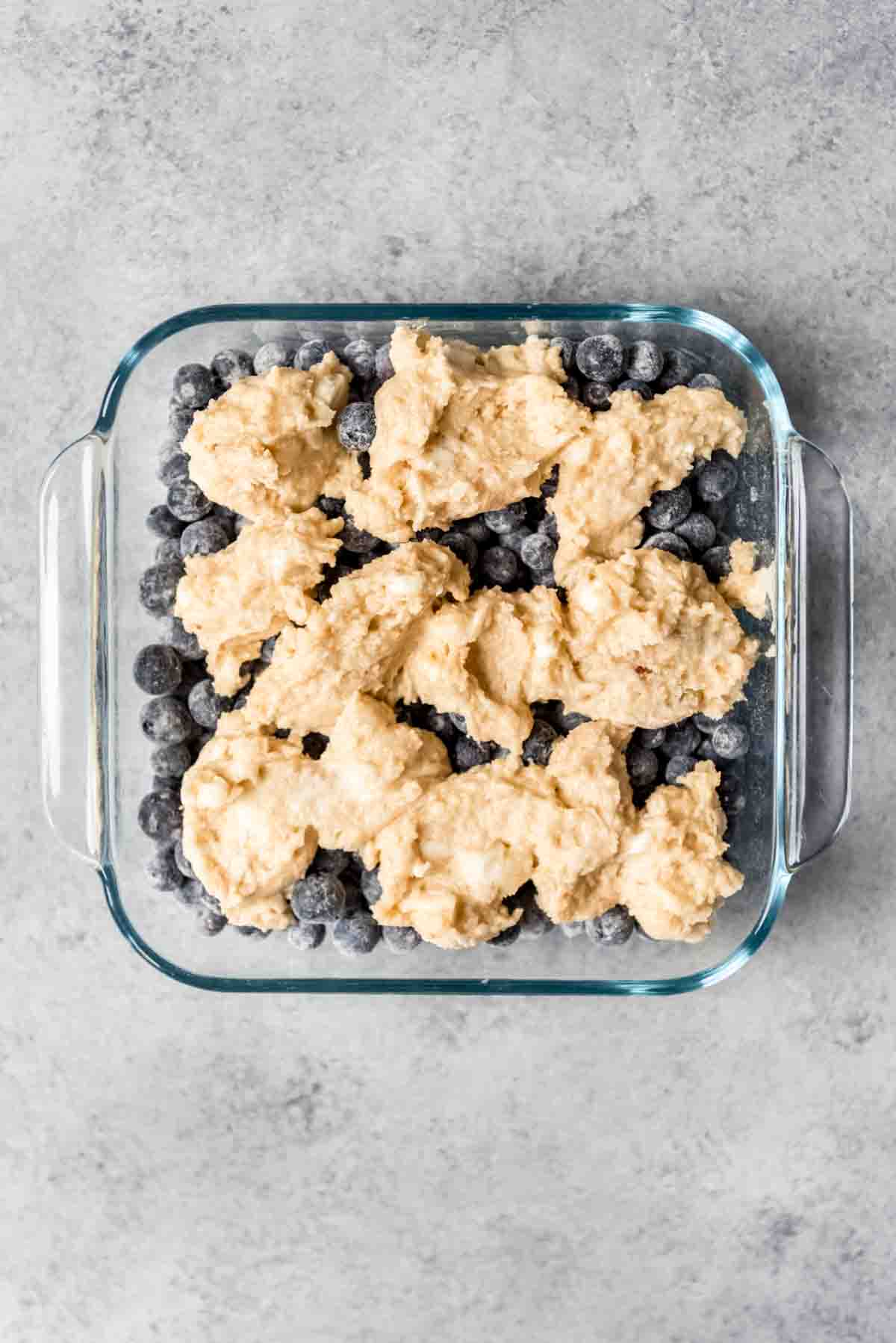 Cobbler topping has been dropped in spoonfuls on top of blueberries. 