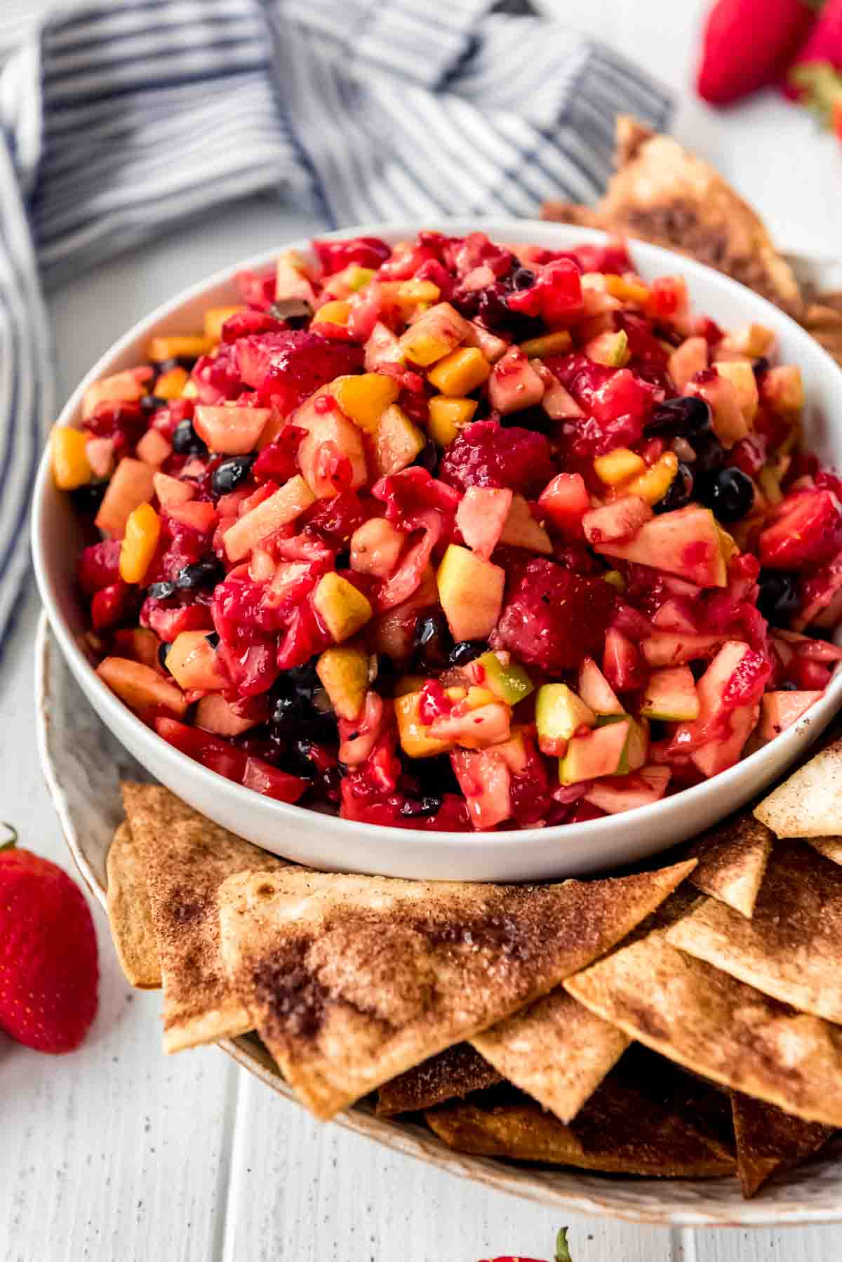 A bowl of fruit salsa with cinnamon chips on the side.