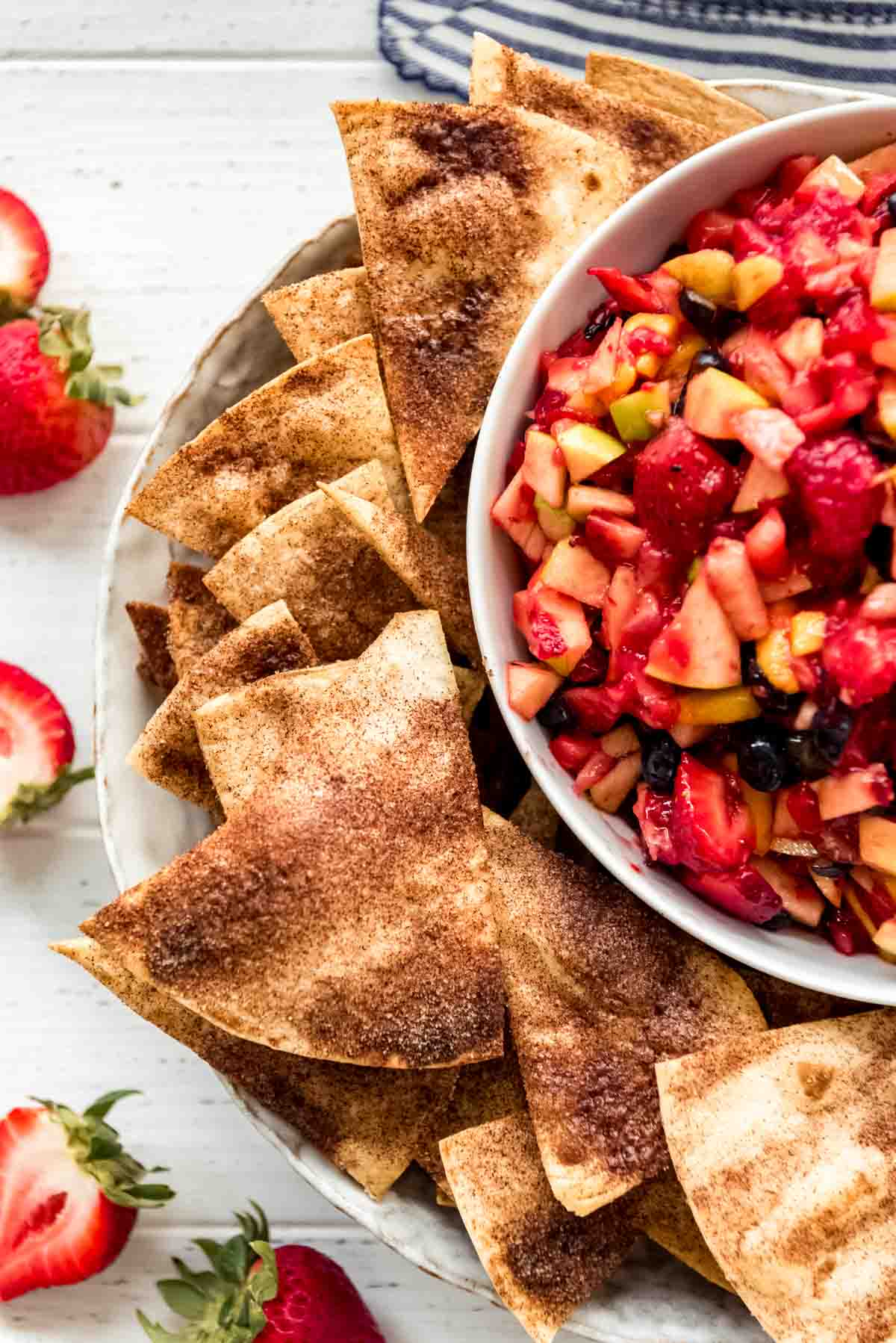 Cinnamon sugar tortilla chips on a plate next to fruit salsa in a bowl.