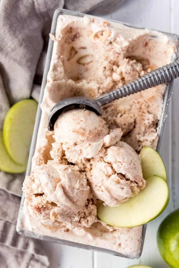a container full of homemade apple pie ice cream being scooped with a metal ice cream scooper
