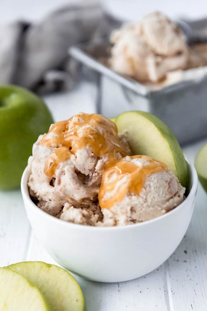 a bowl of apple pie ice cream with caramel sauce and decorated with thin slices of granny smith apple