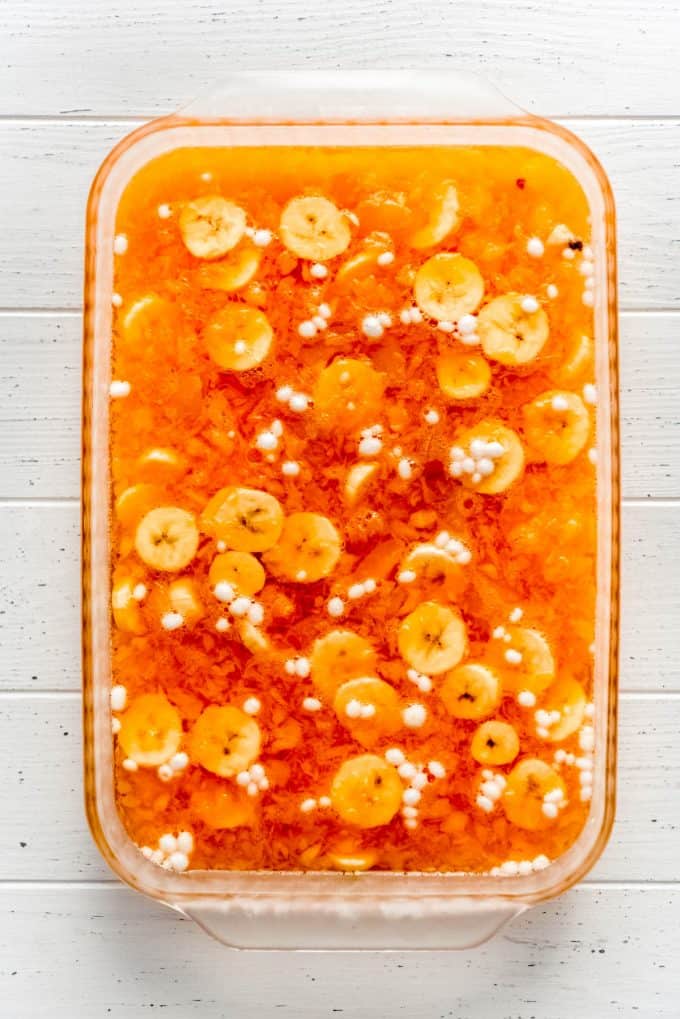 an overhead image of apricot jello with crushed pineapple, bananas and marshmallows