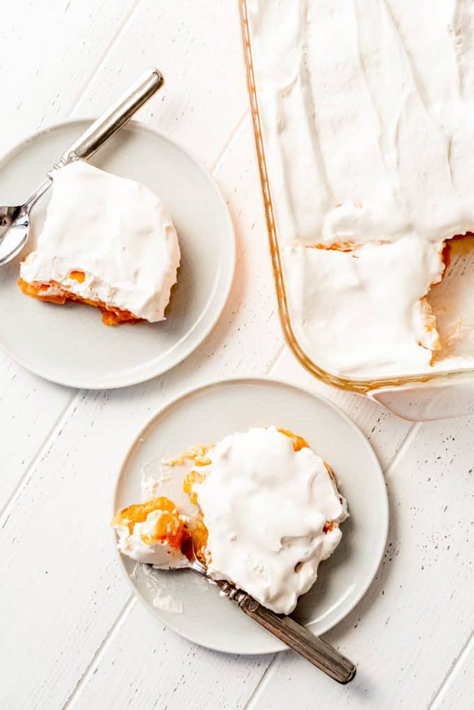 apricot jello on white plates topped with whipped cream