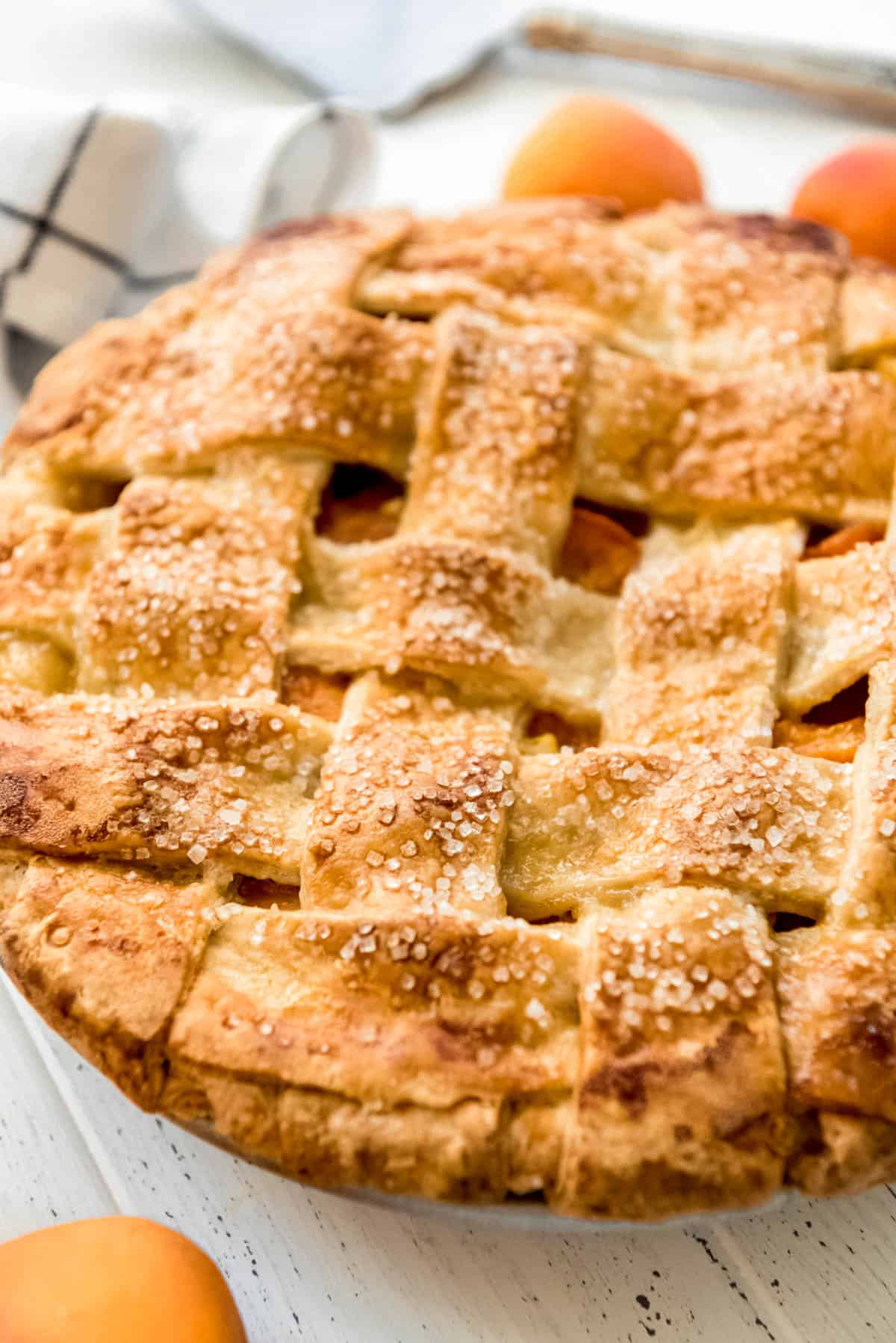 a side angle of a golden brown, flaky pie crust on an apricot pie