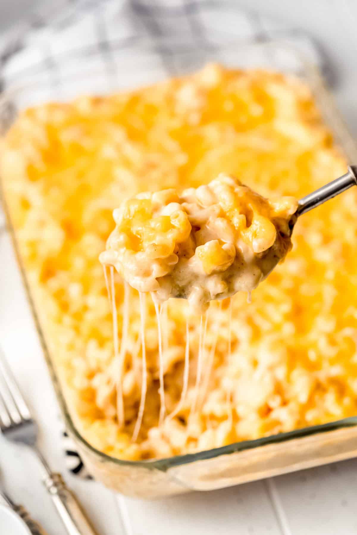 a spoon lifting a scoop of macaroni and cheese out of a baking dish