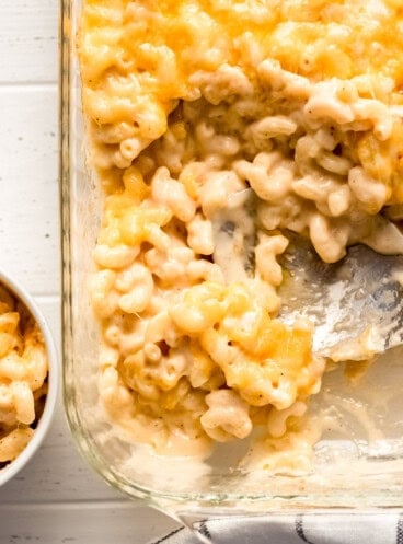 macaroni and cheese being scooped out of a casserole dish