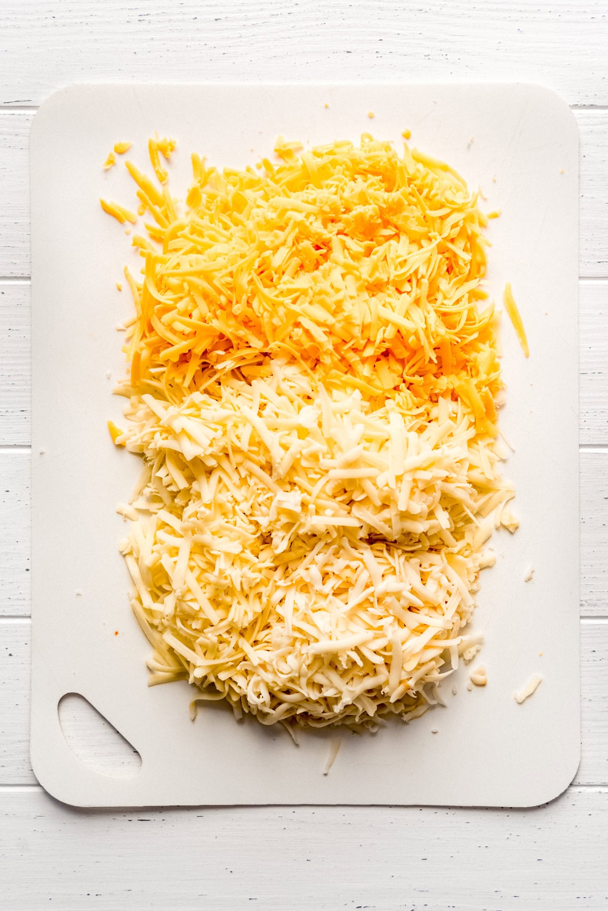 different types of grated cheese on a cutting board