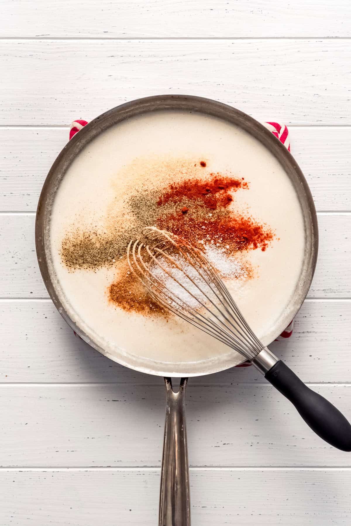 adding spices and seasoning to a creamy sauce