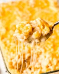 a spoon lifting a scoop of macaroni and cheese out of a baking dish