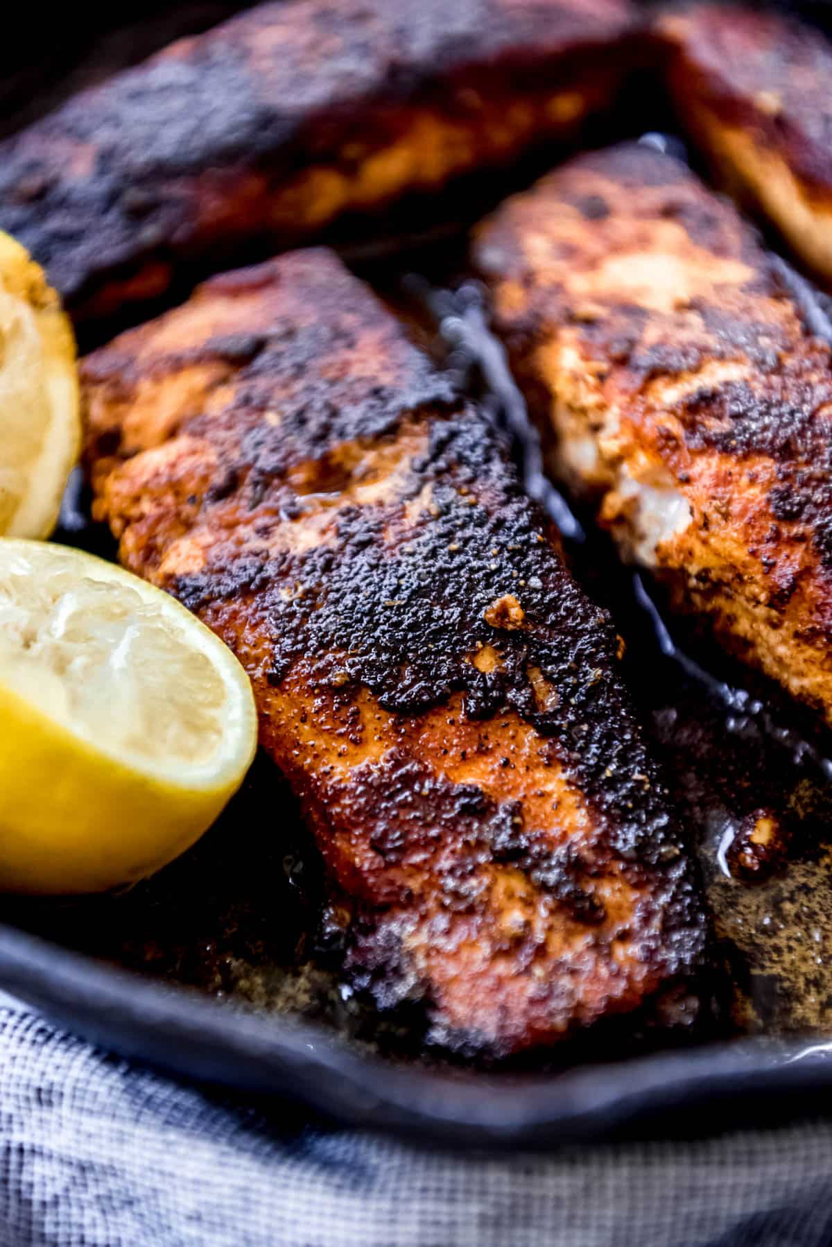 a close image of salmon fillets in a cast iron pan with a blackened crust