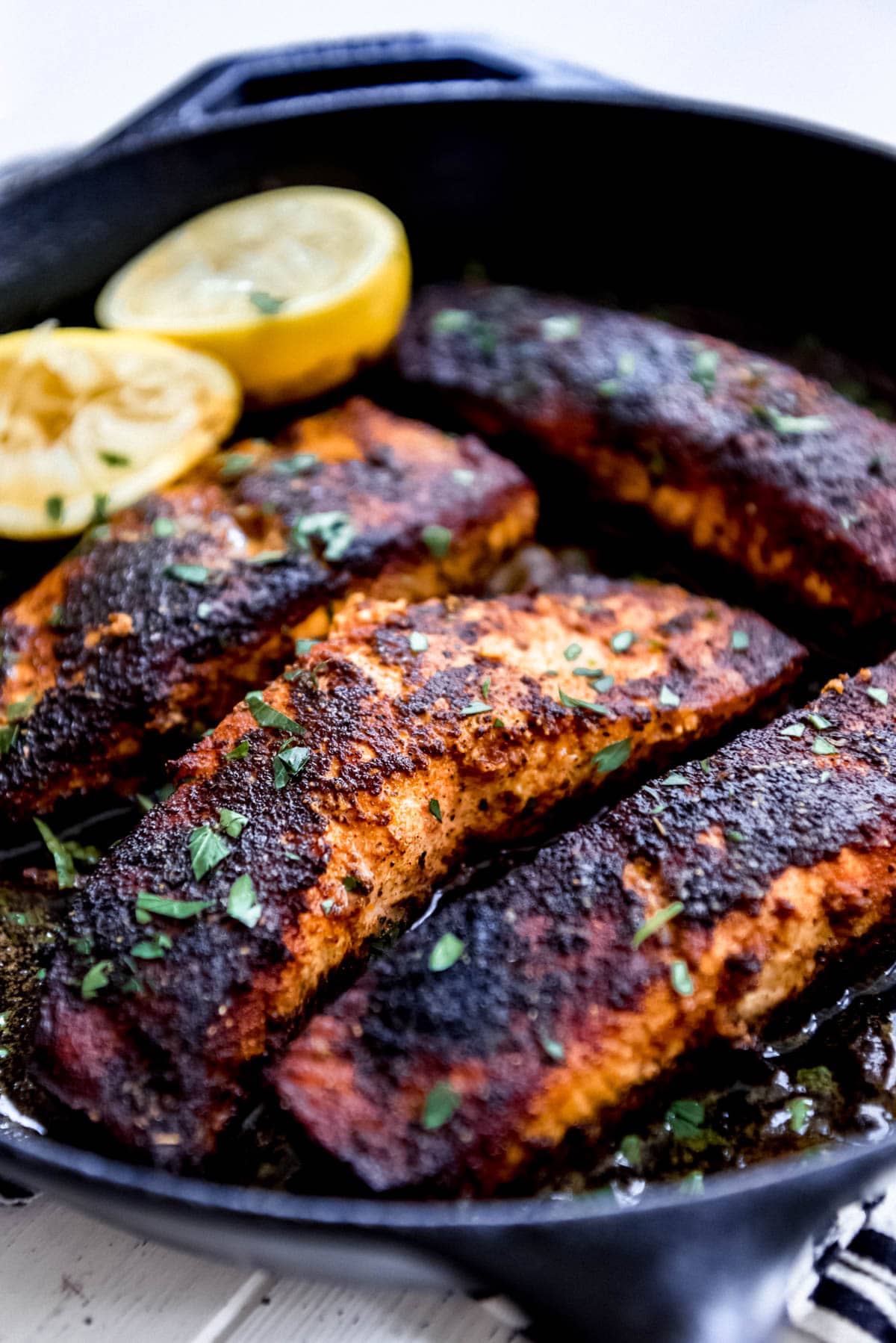 pan seared blackened salmon fillets in a cast iron pan with lemons