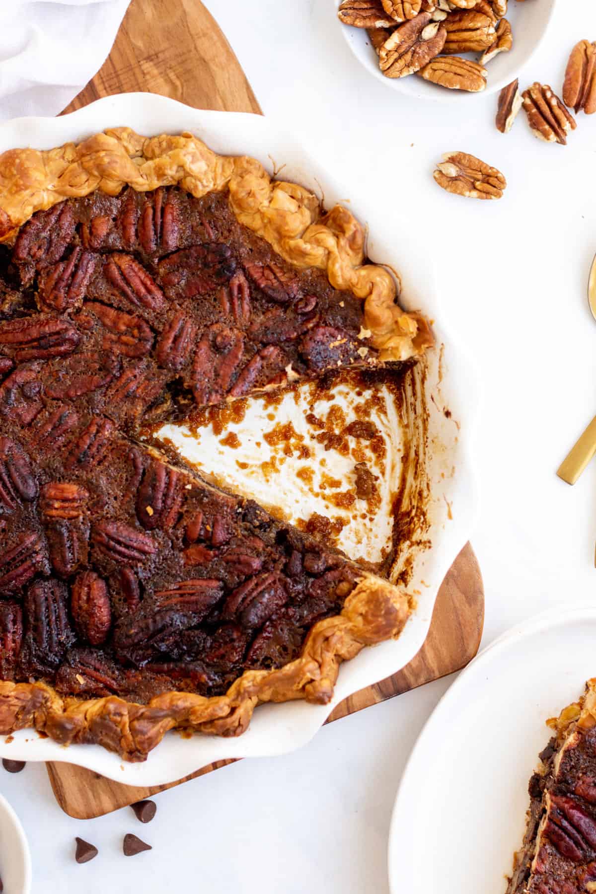 a slice of chocolate pecan pie cut out of a white pie dish