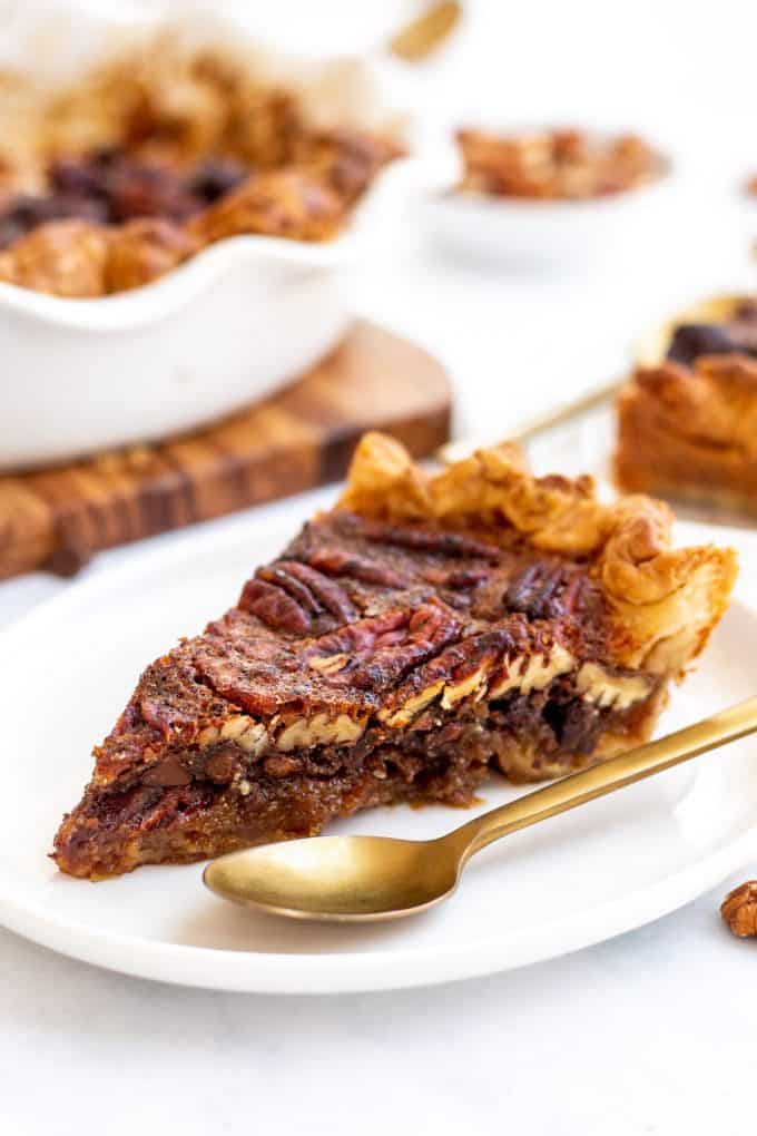 a slice of chocolate pecan pie on a white plate with a gold spoon