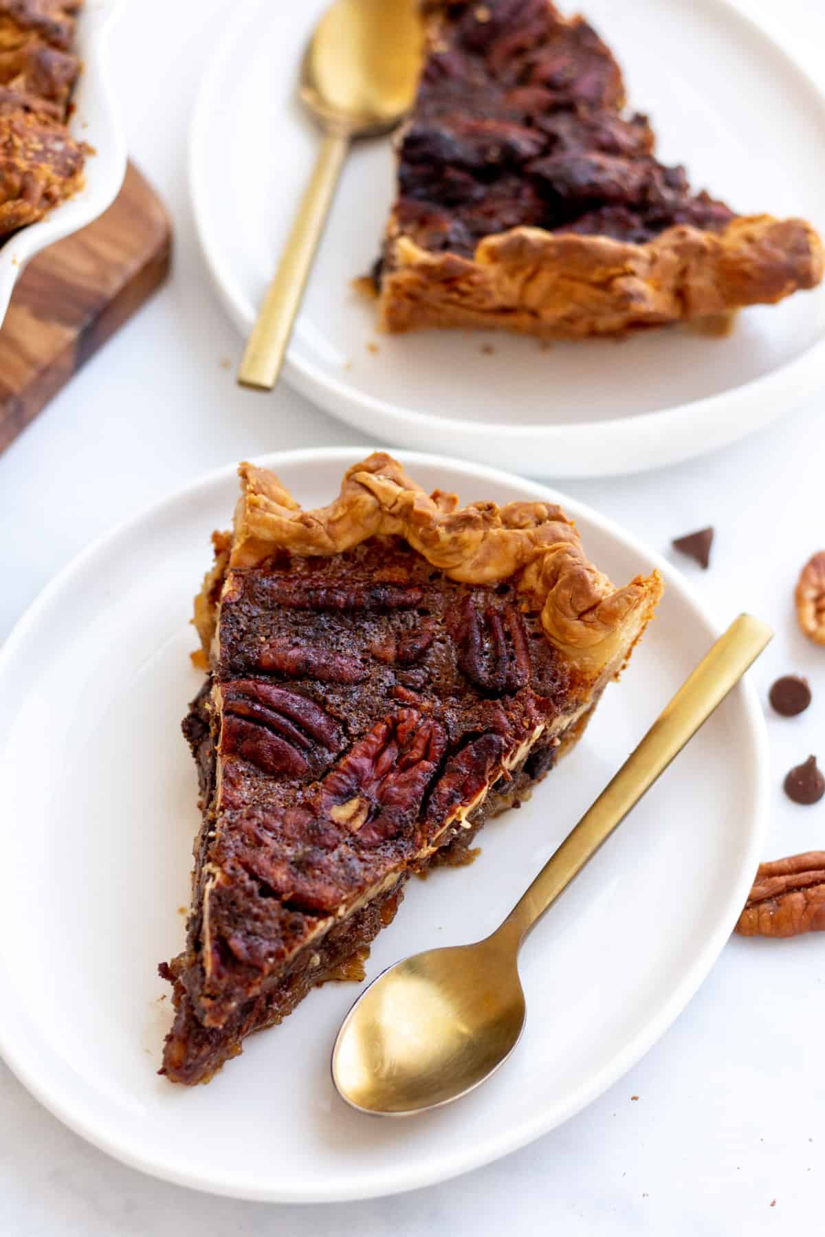 slices of chocolate pecan pie served on a white pie plate with a gold spoon