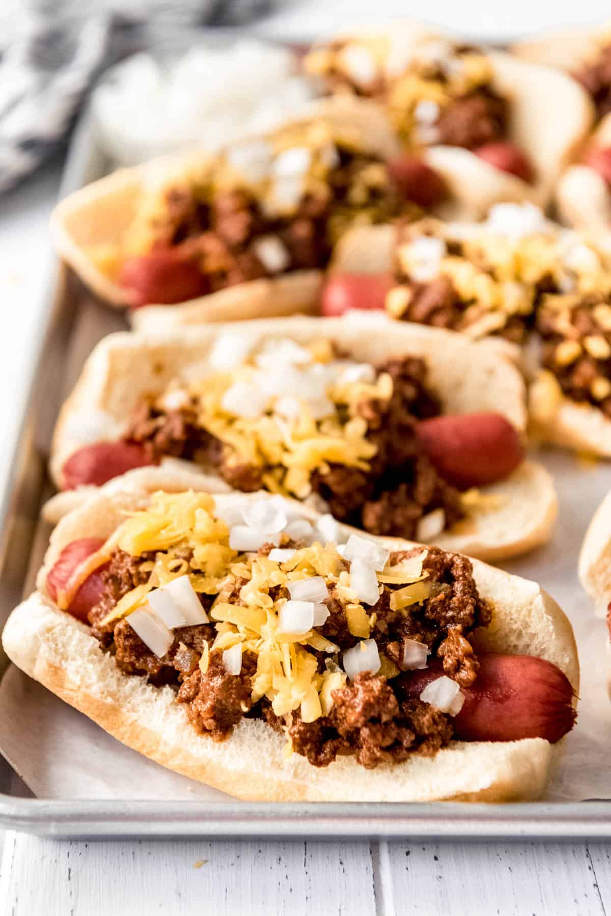 Coney Island hot dogs scattered on a rectangular metal baking sheet. 