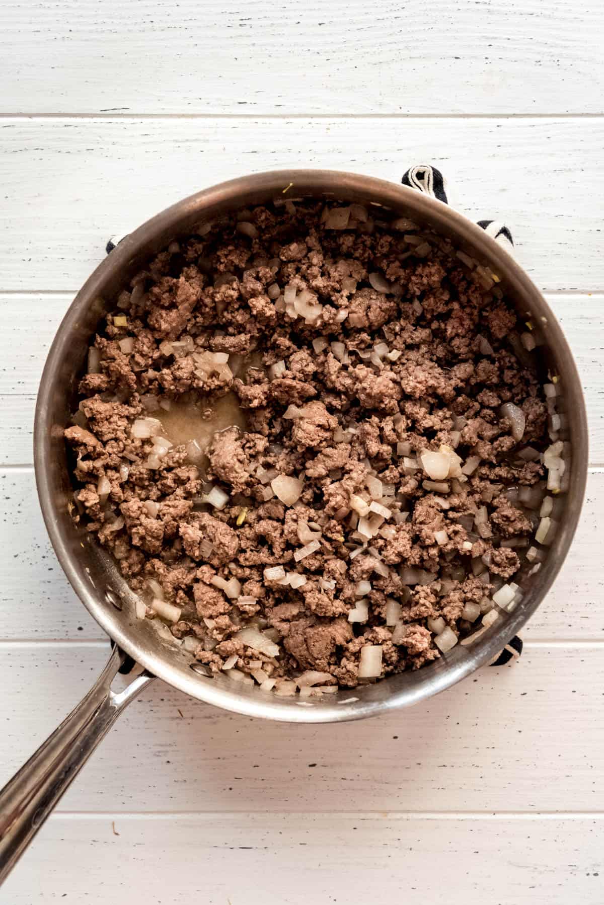 Ground beef and onion mixture in a large skillet after being browned. 