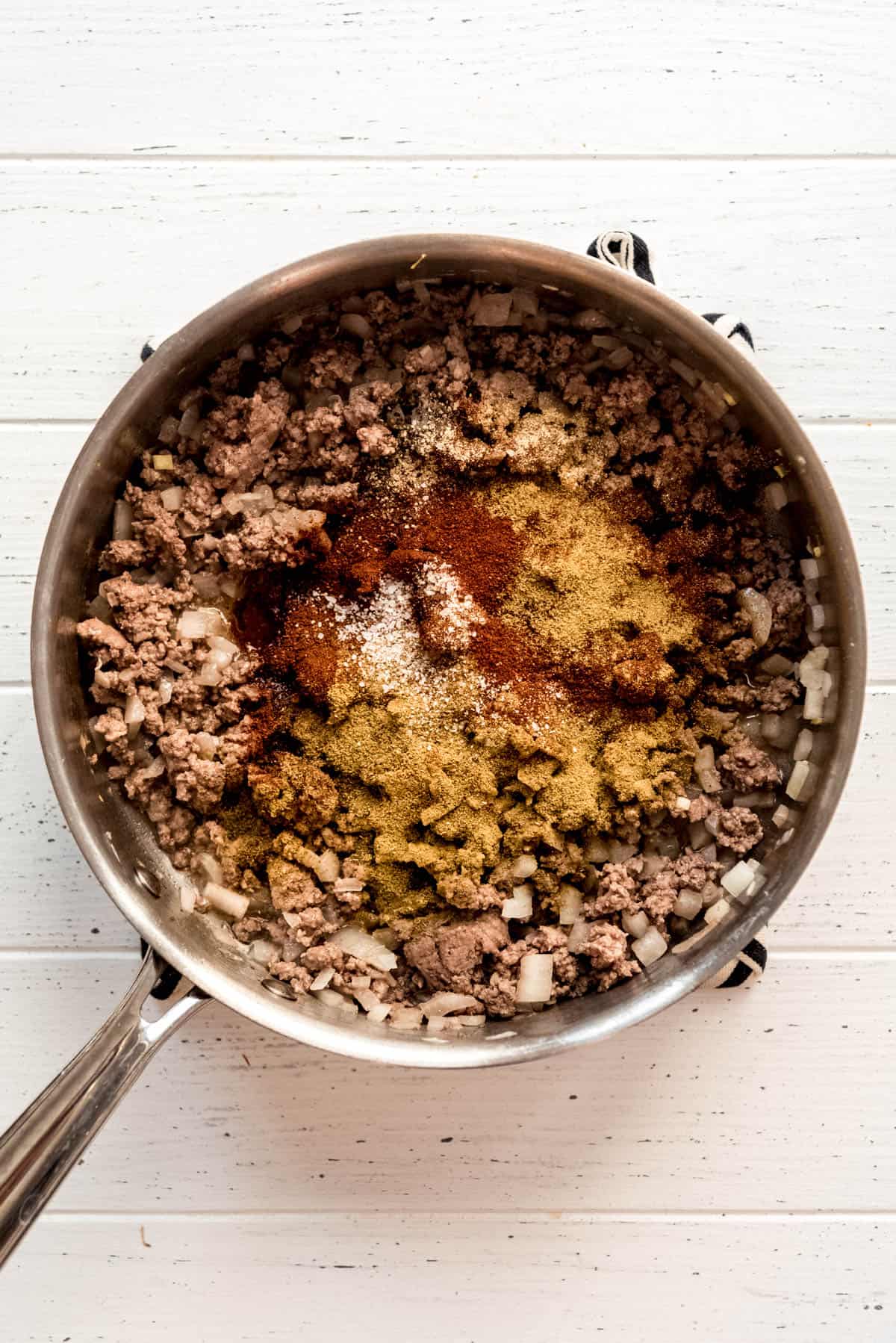 Adding spices to the ground beef mixture. 