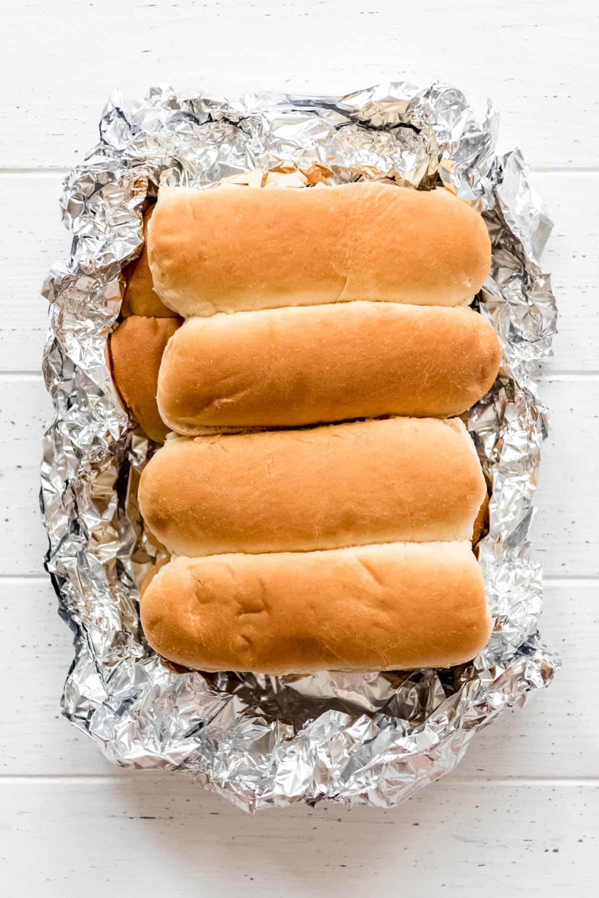 Stacked hot dog buns in foil, ready to be wrapped and heated. 