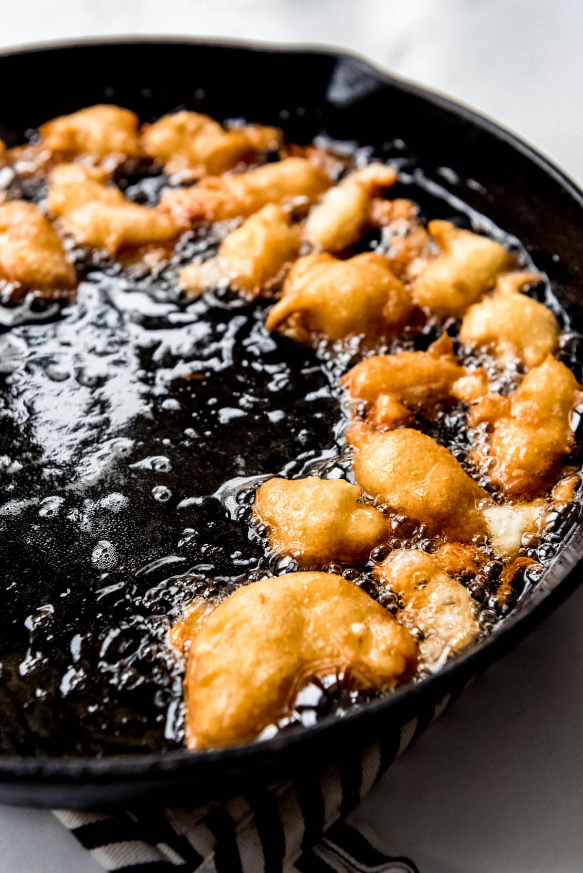 battered fresh cheese curds frying in hot oil in a cast iron skillet