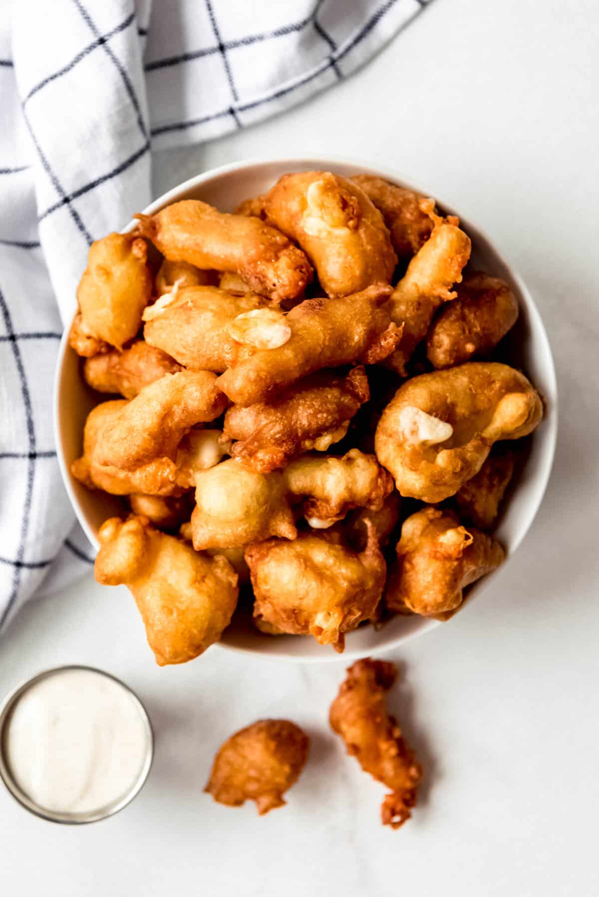 fried cheese curds piled up in a white bowl