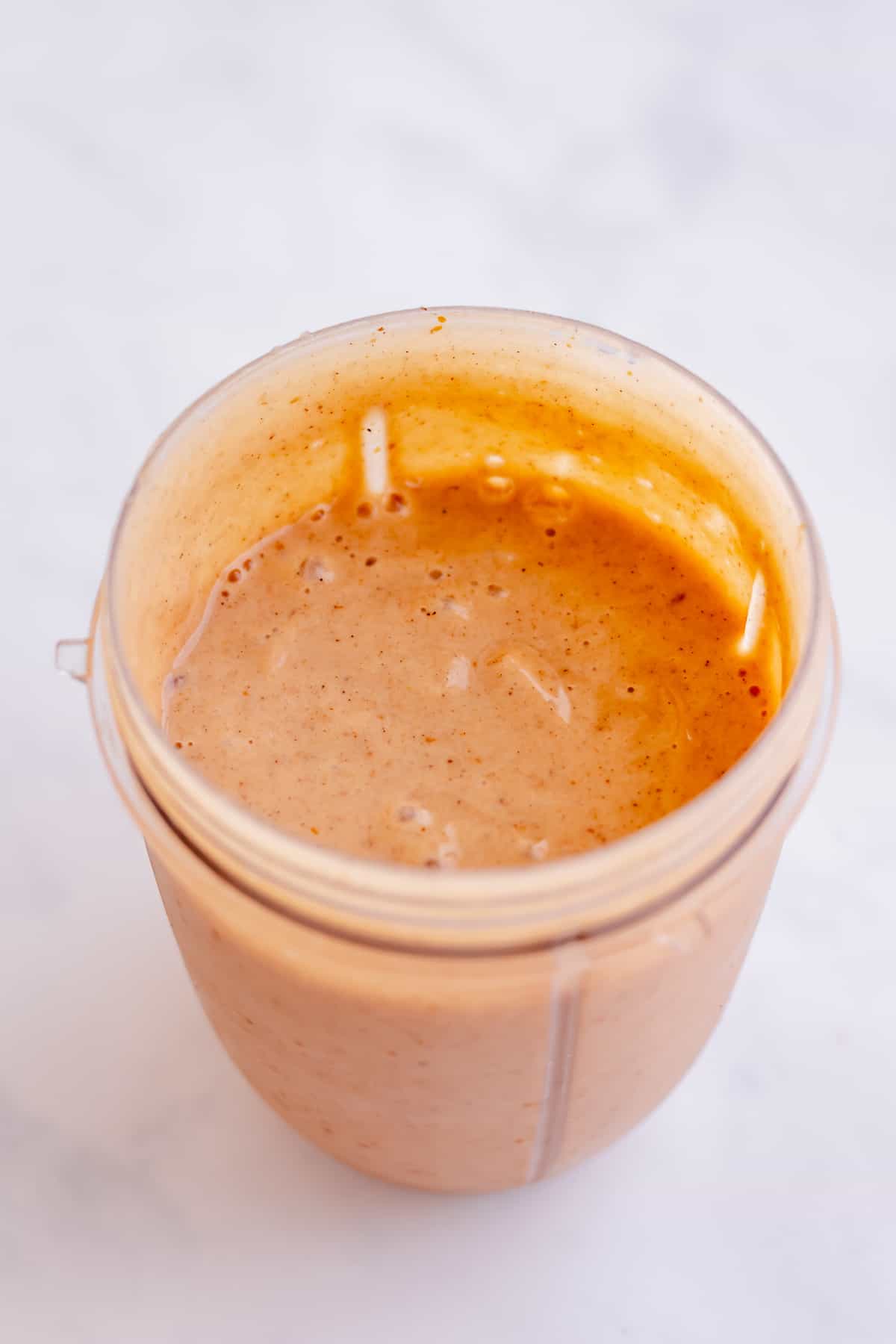 Pumpkin pie ingredients have been blended and are resting in a blender cup. 