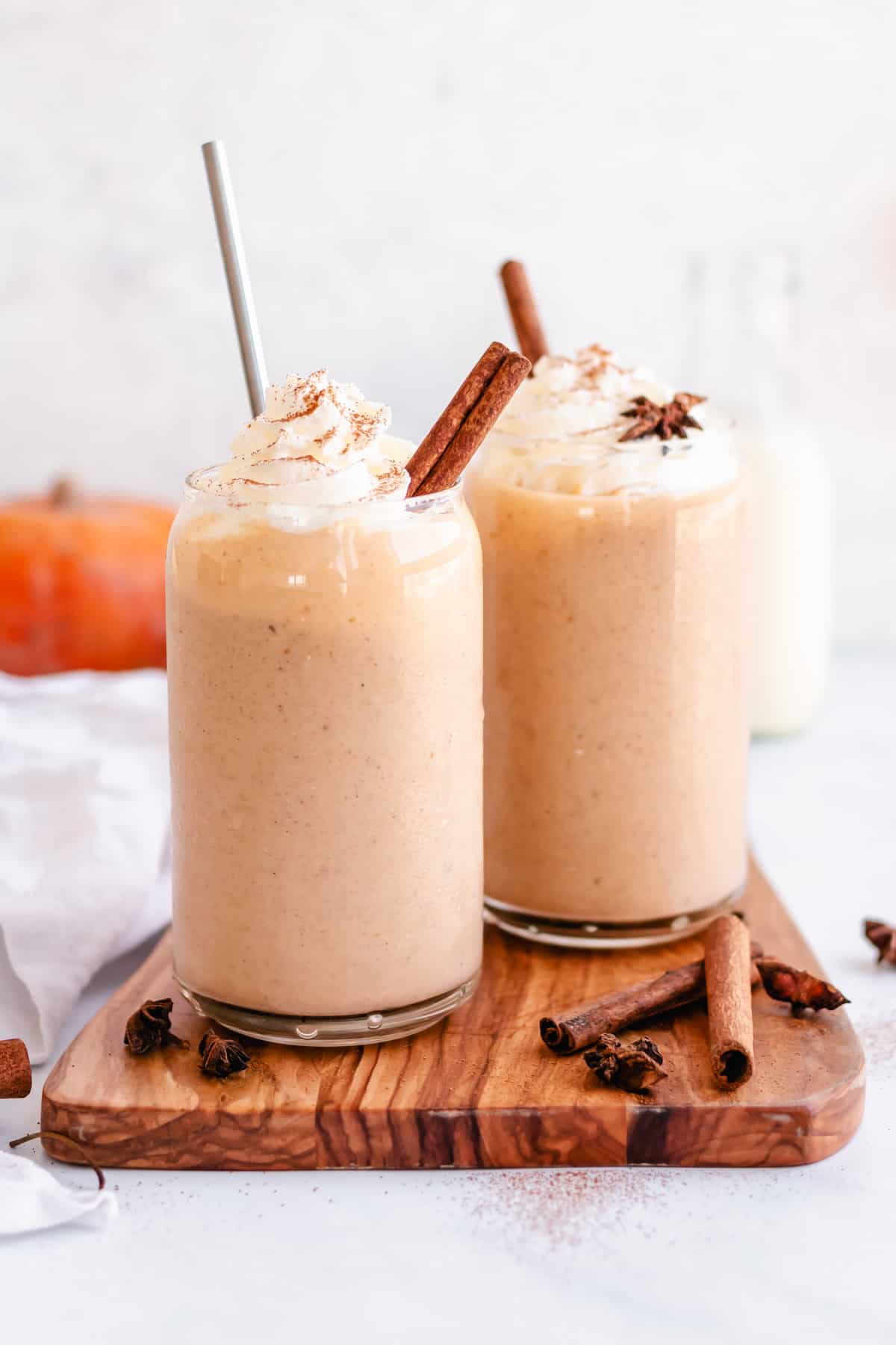 two glasses filled with pumpkin pie smoothie and topped with ground cinnamon