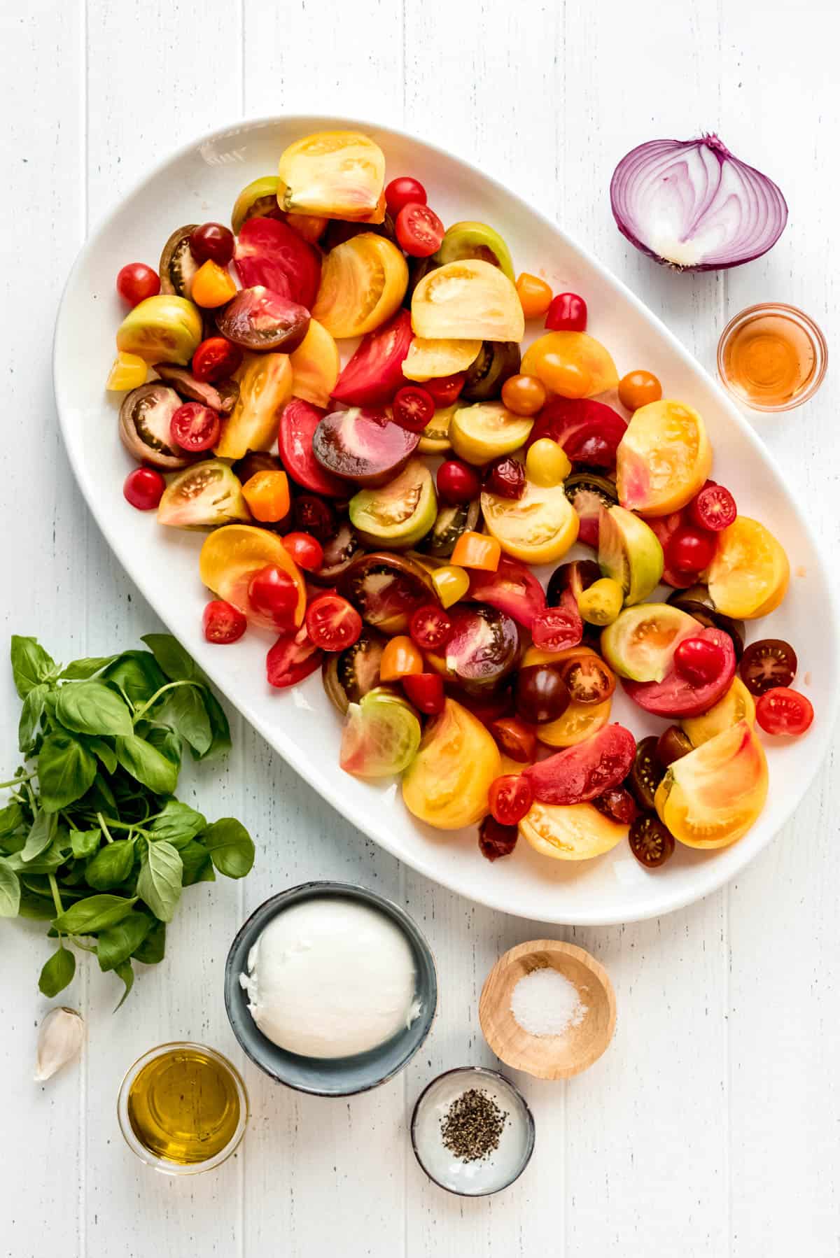 ingredients for an heirloom tomato salad on a white surface