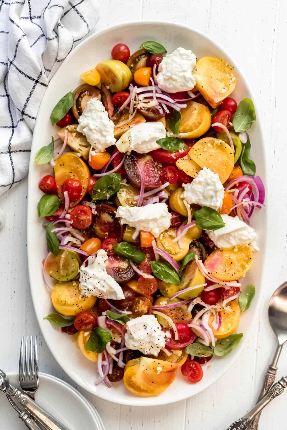 a large white platter filled with a simple heirloom tomato salad