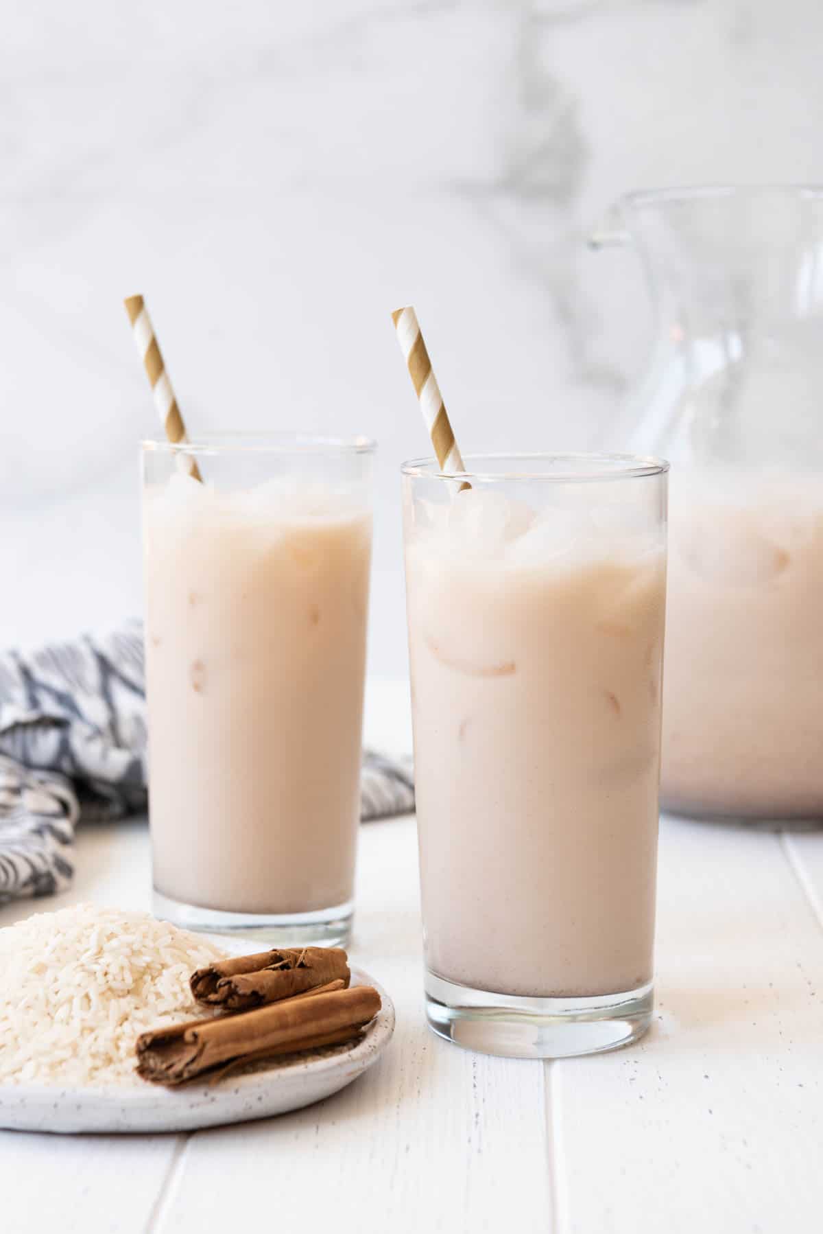 An image of two cups filled with horchata and a striped straw.