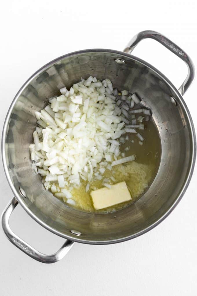 Melting butter in a large pot to saute chopped onion.