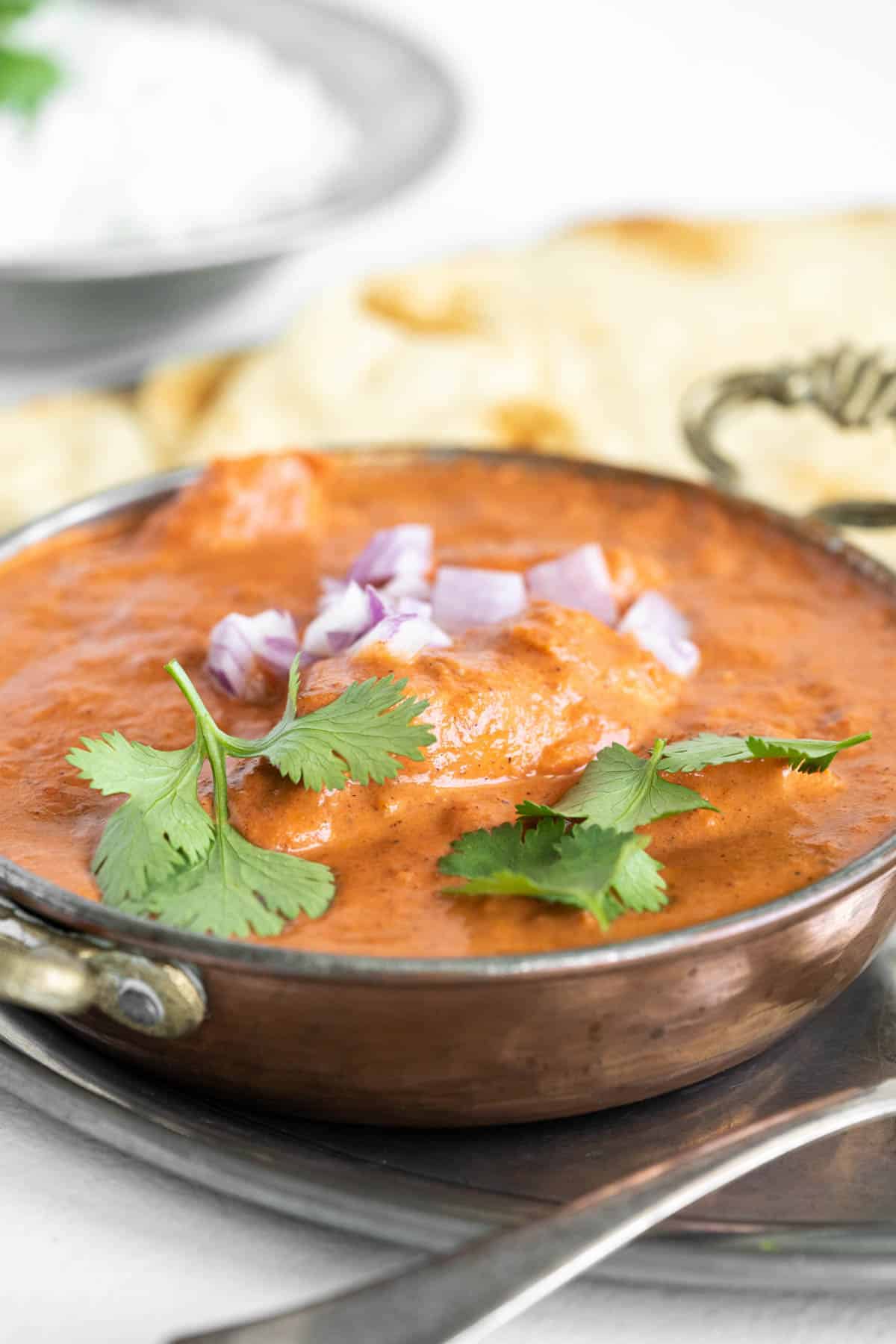 Side view of a bowl of tender Butter Chicken. 