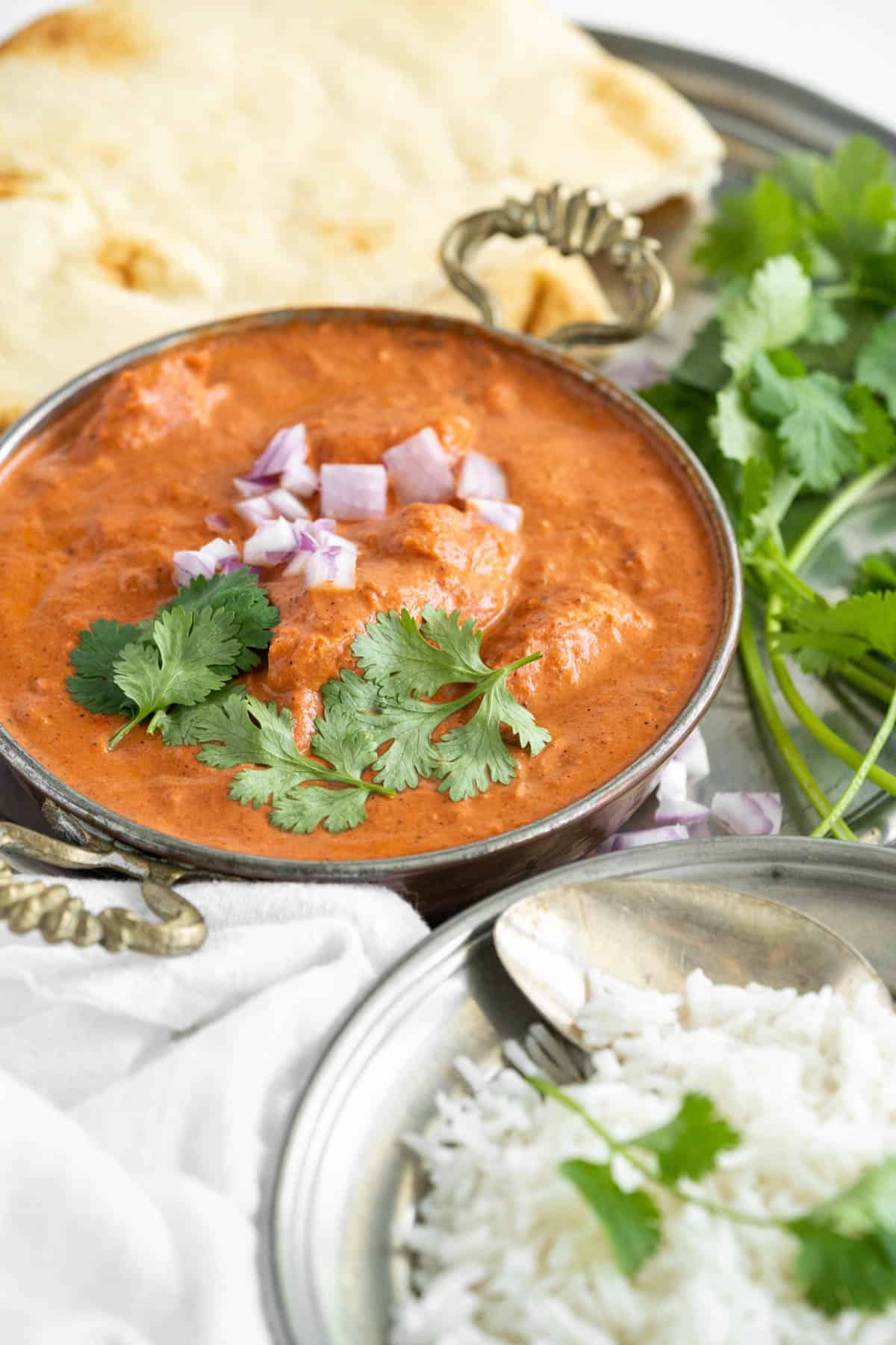 Butter Chicken topped with red onion and cilantro.